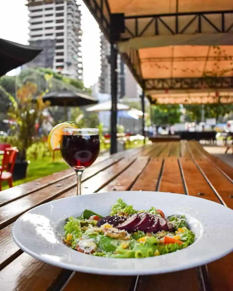 Genießen Sie einen frischen Salat und ein Glas Rotwein in einem Open-Air-Restaurant mit Blick auf die Skyline von Bogotá – perfekt für Veranstaltungen und kulinarische Erlebnisse.