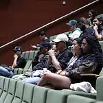 Participants à une conférence ou à une conférence dans un auditorium avec des sièges verts, participant à un événement organisationnel ou universitaire.