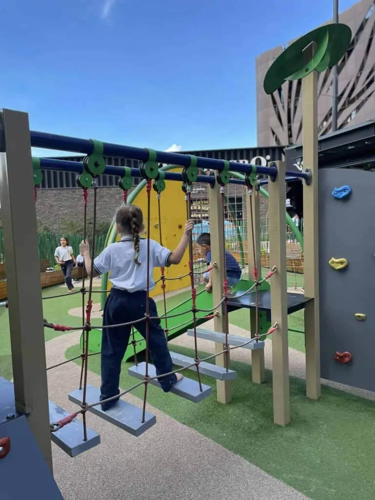 孩子们在户外儿童游乐场玩耍，该游乐场以寓教于乐为理念，是举办儿童活动的理想场所，设有攀爬设施和娱乐游戏。