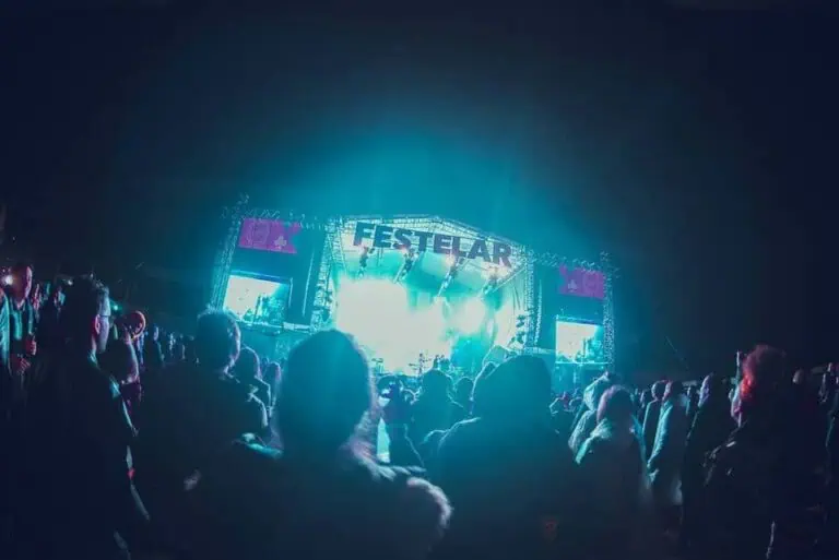 Live performance at an outdoor music festival with a large audience enjoying the concert at night.
