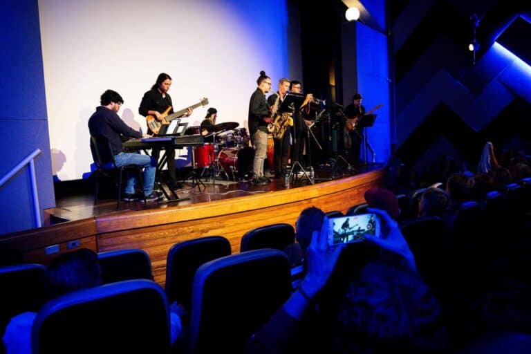 Disfruta de un concierto en vivo con banda musical en un evento de entretenimiento en un espacio moderno y bien iluminado. Reunión artística para eventos culturales y musicales en Colombia.