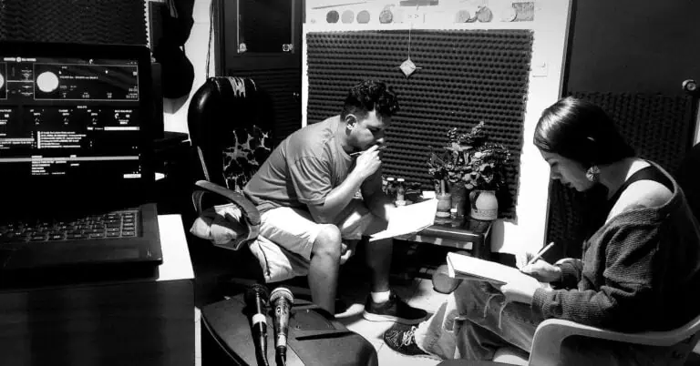 录音棚内，两个人正在使用专业音频设备进行音乐项目录制。