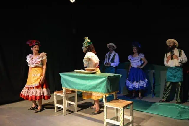 Colorful scene from a traditional play with actors dressed in traditional Colombian costumes on a theater stage.