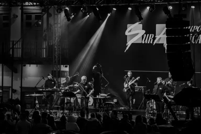 Banda musical en concierto en un evento en vivo, en un escenario con iluminación profesional y público disfrutando la presentación en un ambiente artístico y cultural.