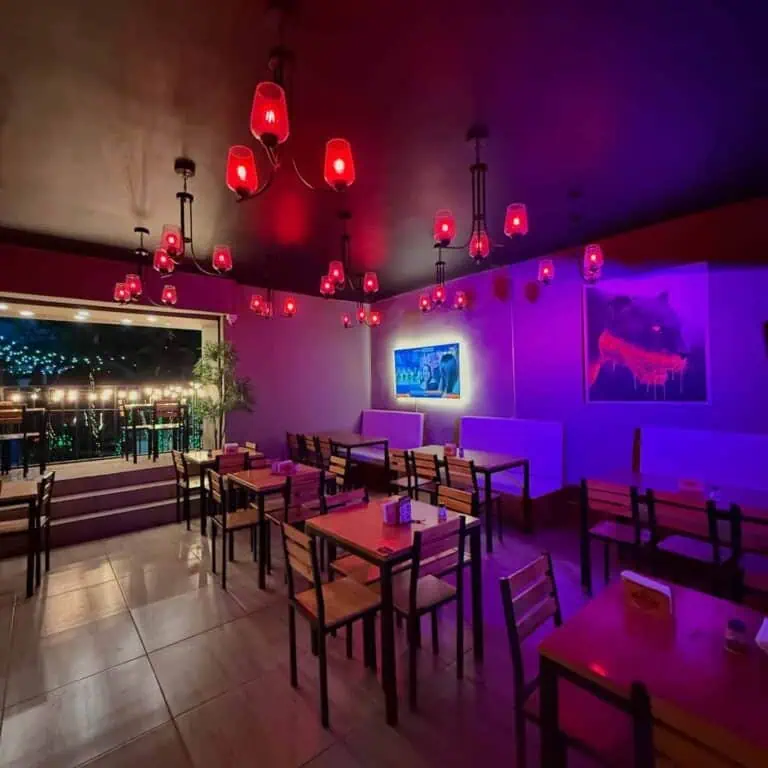 现代餐厅，红色灯光营造出温馨的氛围，配有木桌、电视和墙上的艺术品装饰，是举办活动和社交聚会的理想场所。