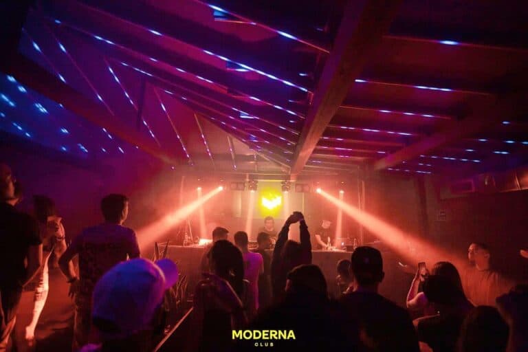 Noche de fiesta en un club nocturno con iluminación de colores y ambiente vibrante, con personas disfrutando de la música y el espectáculo en un evento organizado por Eventario.