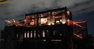 Amplia vista del moderno centro de eventos iluminado en la noche, con estructura de cristal y luces de neón, ideal para reuniones y celebraciones exclusivas en Colombia.