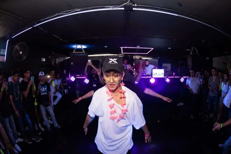 Person dancing at a night event with a party atmosphere, disco lights, DJ and audience enjoying and capturing moments, at an event organized by Eventario.