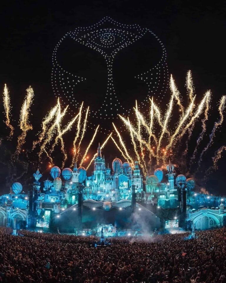 Espectáculo de fuegos artificiales y luces en un concierto temático Disney en un parque de atracciones durante la noche, con una multitud de asistentes disfrutando del evento.
