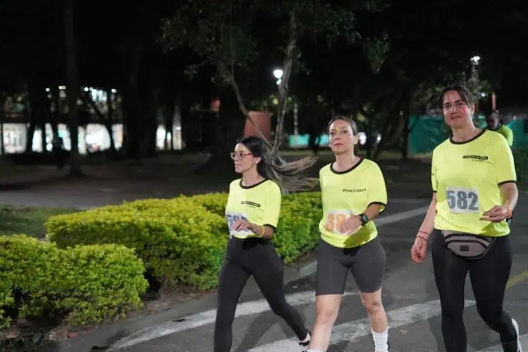 Runners participating in a night run in a park, wearing yellow jerseys and race numbers, promoting sporting events and community wellness.