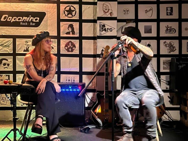 Voz en vivo de una banda de rock en un bar con paredes decoradas con arte y logos, ambiente relajado y musical, ideal para eventos y conciertos en Bogotá.