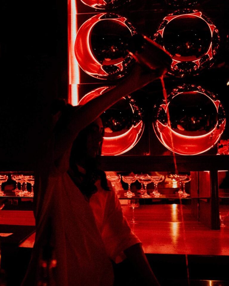 Espectacular imagen de un evento en un bar con iluminación roja y decoraciones modernas, ideal para promocionar eventos y experiencias únicas en la organización de eventos en Colombia.