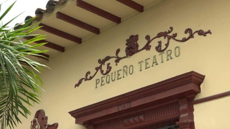Puerta de un teatro con nombre pequeño y decoraciones vintage en estilo colonial, fachada en colores cálidos, ideal para eventos culturales y teatrales en Colombia.