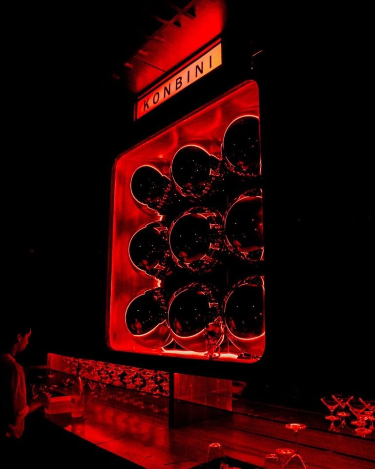 Esquina moderna de evento con exhibición de objetos decorativos en iluminación roja, en un espacio innovador y con ambientación elegante.