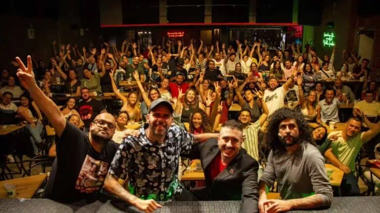 Menschen bei einer Veranstaltung in einer unterhaltsamen und netzwerkenden Atmosphäre in einem farbenfroh beleuchteten Raum, wobei die Teilnehmer bei einem gesellschaftlichen und beruflichen Event in Kolumbien Spaß haben und lächeln.
