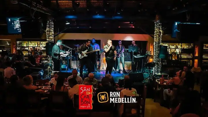 在麦德林的一家餐厅里，现场乐队正在演出，观众们正在享受夜晚的氛围，灯光柔和，舞台专业，是举办活动和娱乐的理想场所。