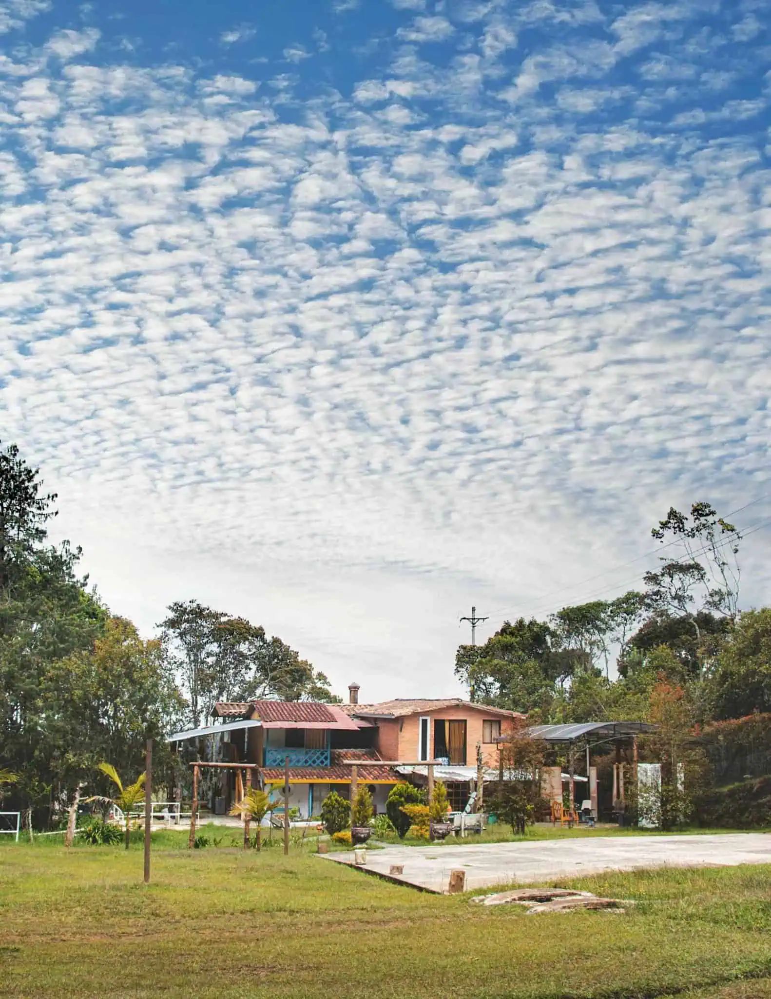 Casa de campo em meio à natureza, com céu nublado, ideal para eventos e encontros ao ar livre na Colômbia. Espaçosa e rodeada de vegetação, perfeita para desfrutar com a família e os amigos.