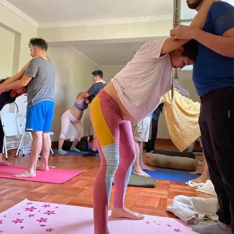 Prática de yoga em grupo durante um workshop de bem-estar em um espaço interno com madeira e luz natural, promovendo relaxamento e atenção plena.