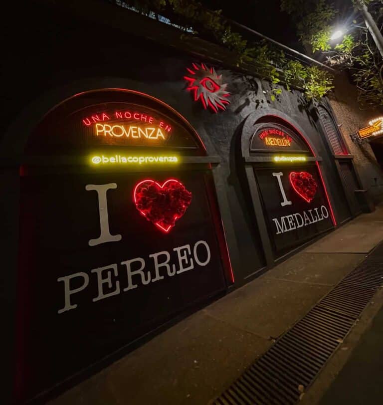 Luces de neón con frases y corazones en una fachada de evento en Medellín, promoción de noche romántica con temática de queso y medalla, ideal para marketing de eventos y experiencias en ciudades colombianas.