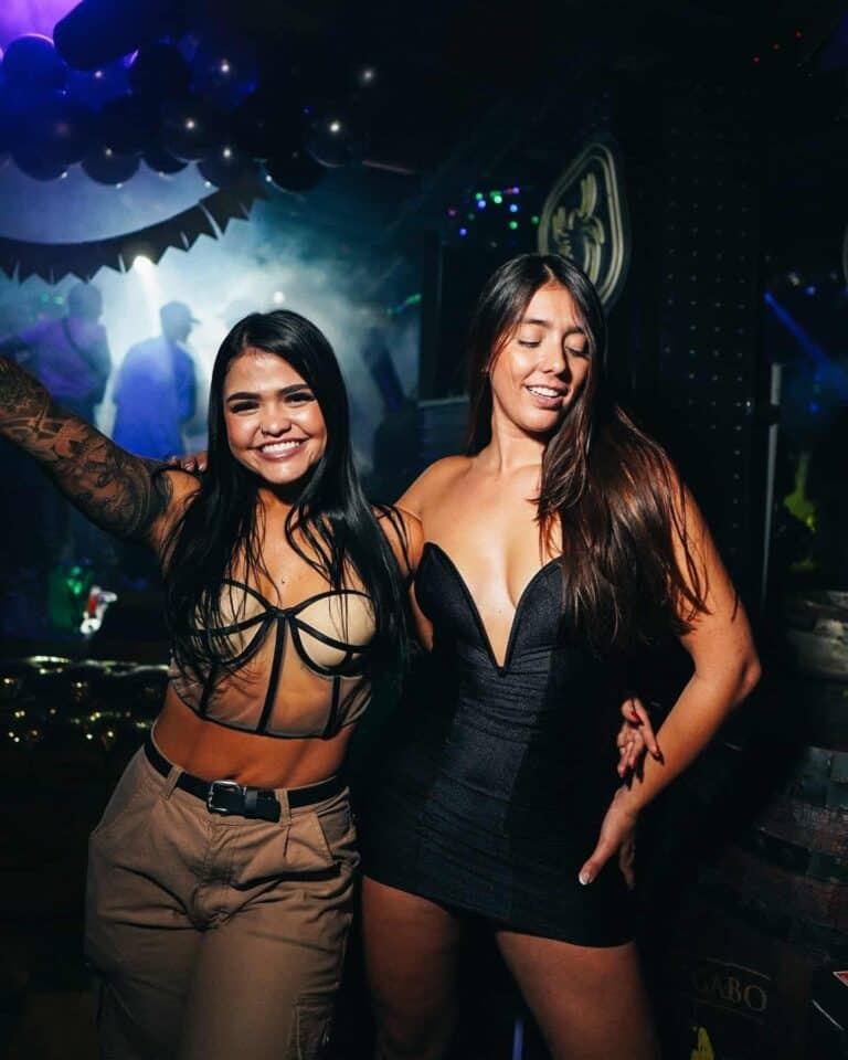 Diversas personas disfrutando en una fiesta nocturna con ambiente vibrante y luces de discoteca en un club.