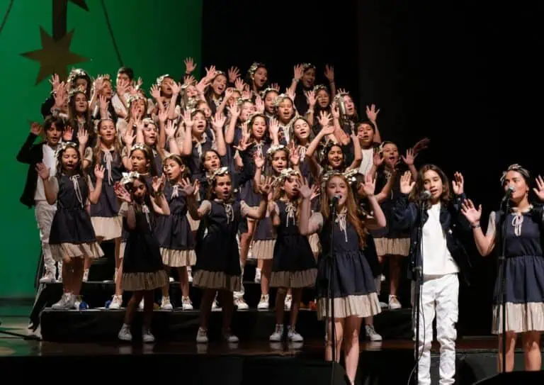 Des enfants chantent lors d'un concert scolaire en uniforme, sur la scène d'un événement culturel pour enfants en Colombie.