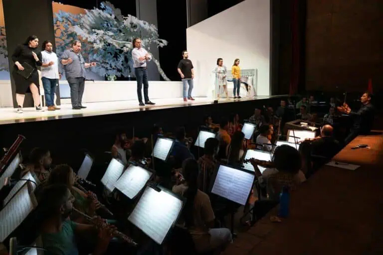 Représentation théâtrale en direct avec des acteurs sur scène devant un orchestre dans une salle de concert, pour des événements culturels et artistiques, promouvant des expériences culturelles en Colombie.