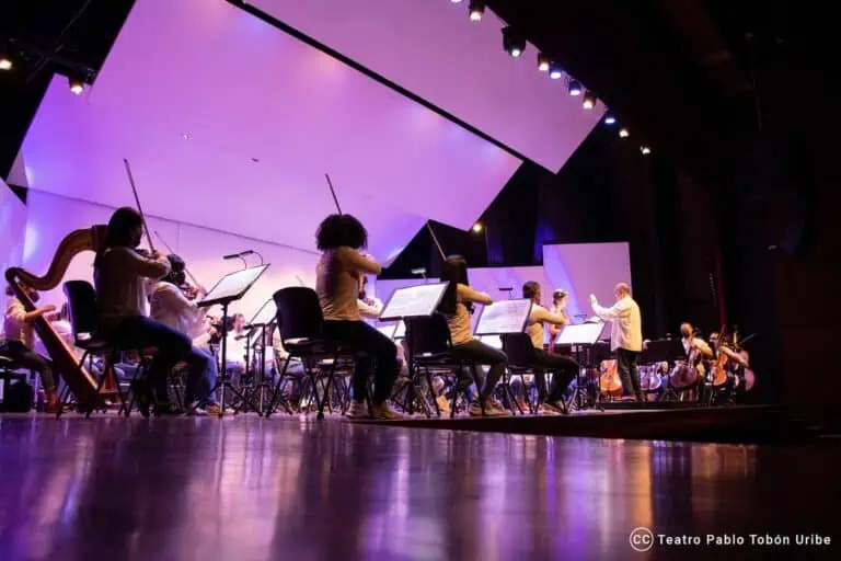 现场管弦乐队在剧院内排练，配有环境灯光、音乐表演和舞台艺术。