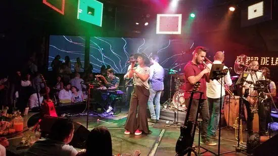 Célébration dans un lieu avec des performances live, de la musique et un public profitant de l'événement dans une ambiance vibrante et artistique.