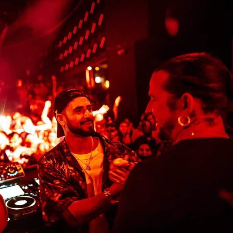 DJ interactuando en una fiesta con ambiente oscuro y luces rojas en un evento de música electrónica.