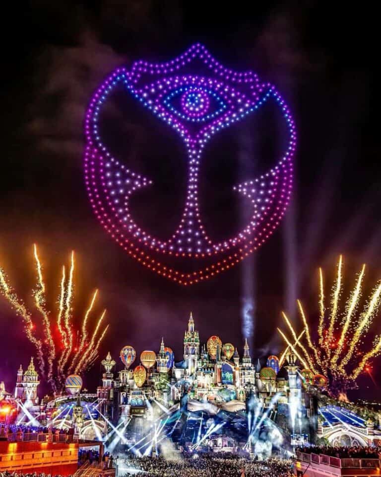Fiesta de fuegos artificiales en un parque temático con un espectáculo de luces y un diseño de LED en forma de rostro en el cielo, ideal para eventos y celebraciones en vivo.
