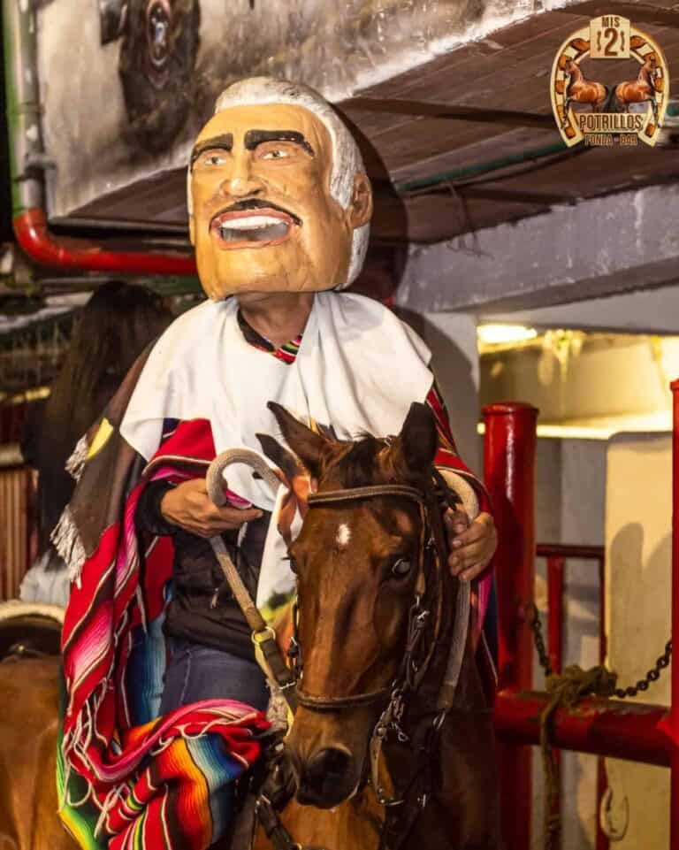 Caballero con máscara tradicional indígena montando un caballo en evento cultural Motivo de celebración en Colombia con poncho colorido y ambiente festivo.