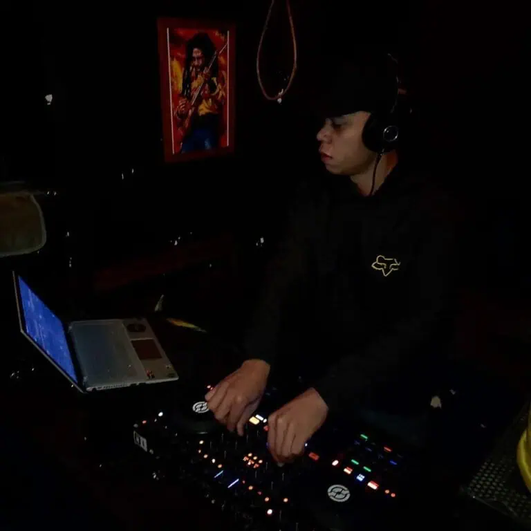 一位DJ舞者在活动现场使用专业设备进行混音表演。昏暗的灯光、墙上的艺术品和耳机营造出沉浸式的音乐体验。