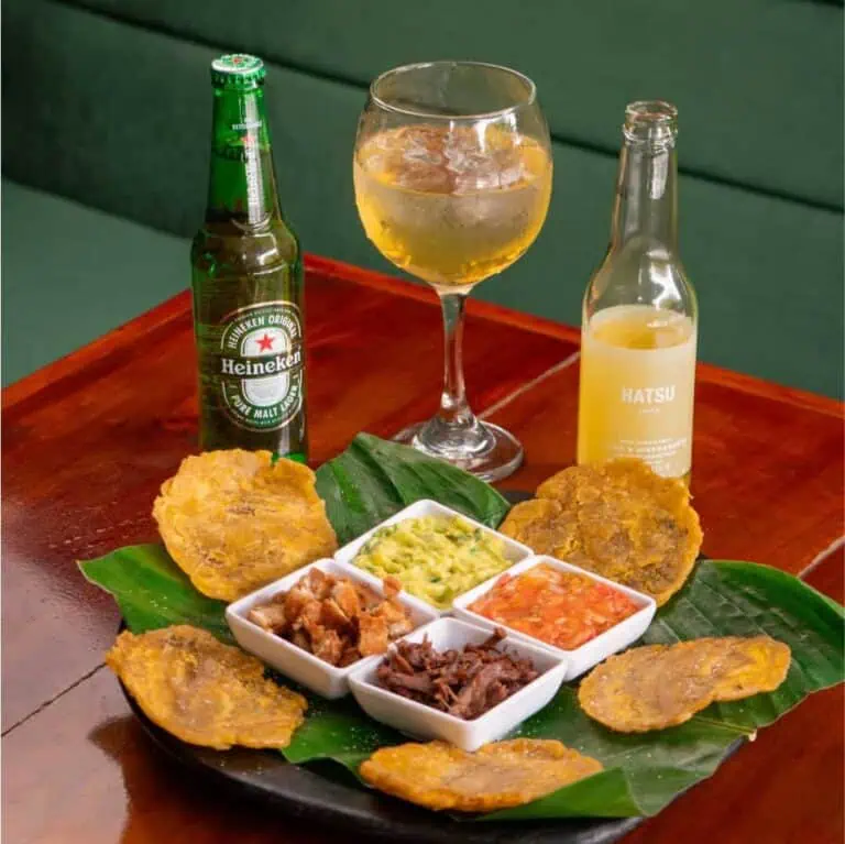Verre et bouteilles de bière avec des collations traditionnelles colombiennes sur une table en bois.
