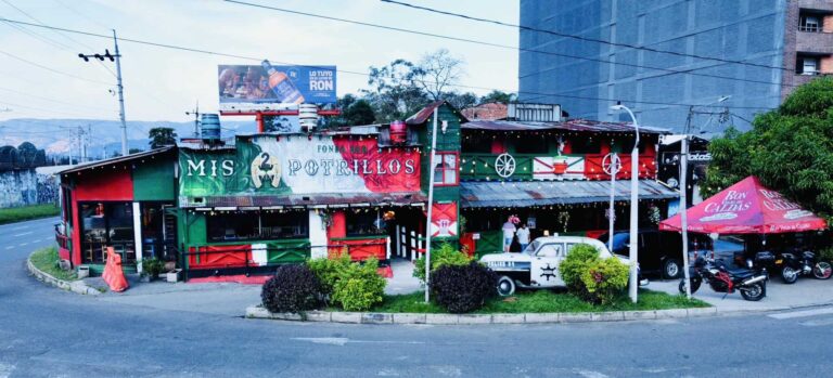 Colorido restaurante en zona urbana con decoración temática y motos estacionadas, ideal para eventos y reuniones sociales en Colombia.