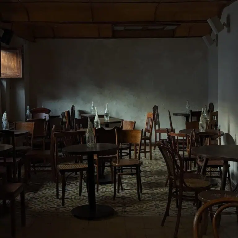 餐厅内部装潢昏暗，配有木桌、椅子和装饰瓶，灯光昏暗，是波哥大举办专属活动和私密晚宴的理想场所。