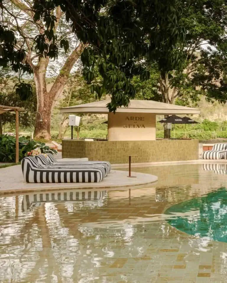 Relaxing poolside lounge chairs in a natural setting, ideal for events and parties surrounded by nature, with shaded trees and a peaceful atmosphere, perfect for enjoying the day.