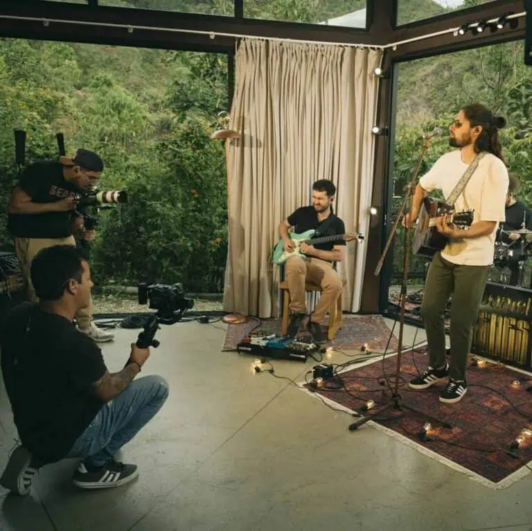 Une image de musiciens en direct se produisant lors d'un événement en plein air, enregistrée par une équipe audiovisuelle dans un cadre naturel surplombant des zones vertes et montagneuses, promouvant le divertissement et la culture lors d'événements en pleine nature.