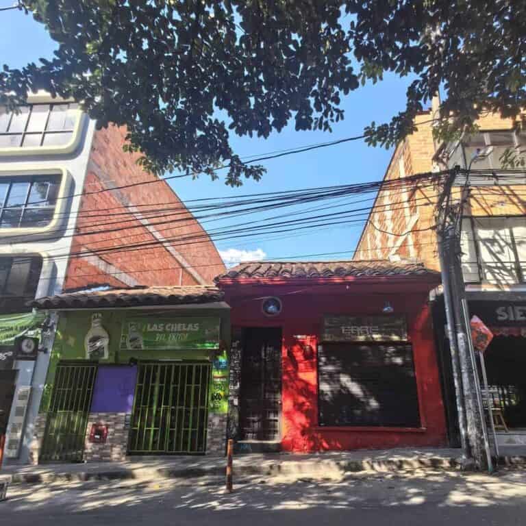 Colorida fachada de comercio en calle urbana con árboles y cables eléctricos, mostrando un ambiente local y comercial en Bogotá, Colombia.