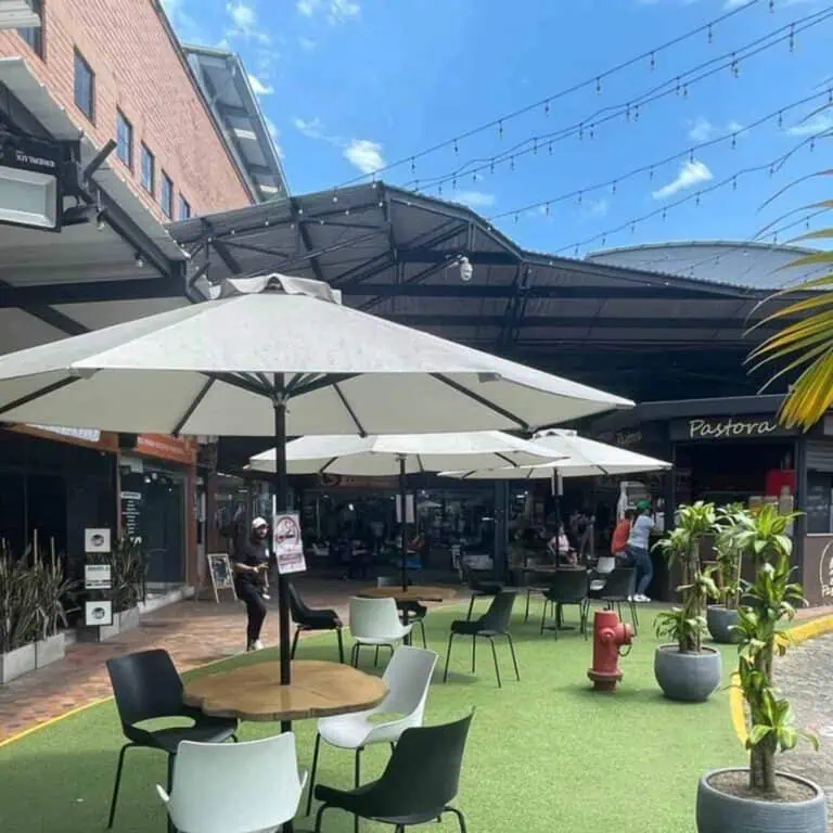 Restaurantterrasse mit Sonnenschirmen und Außentischen in einem Einkaufszentrum, moderne und einladende Atmosphäre, ideal für Veranstaltungen und gesellschaftliche Zusammenkünfte, in Bogotá, Kolumbien.