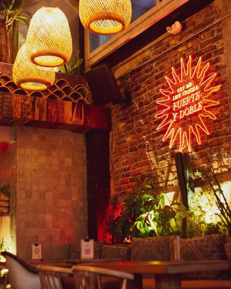 Wicker lamps provide warm light, a cozy atmosphere in a restaurant with brick walls and modern decor, ideal for events and social gatherings in Colombia.