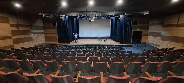 Présentations dans un auditorium moderne, avec une scène avec projecteur et des chaises confortables, pour des événements et des conférences en Colombie.