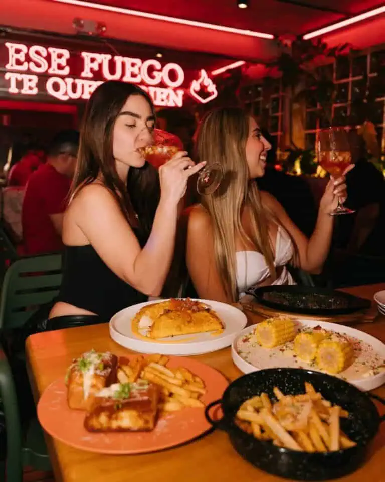 Enjoying food and cocktails in a restaurant with a lively atmosphere and neon lights.