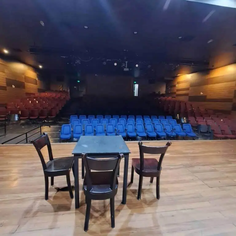 Grand théâtre ou salle d'événements avec loge et chaises bleues et rouges, idéal pour présentations, conférences et spectacles dans un espace moderne et bien équipé.