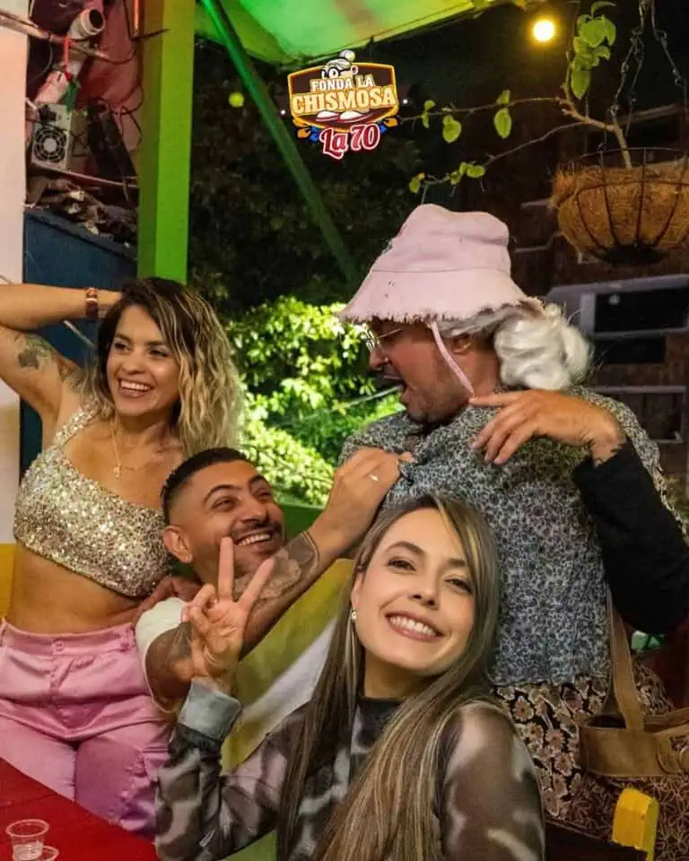 Una divertente festa con gli amici in un ristorante decorato con luci e piante, godendosi una festa a tema con un uomo in costume e persone che sorridono e fanno il segno della pace.