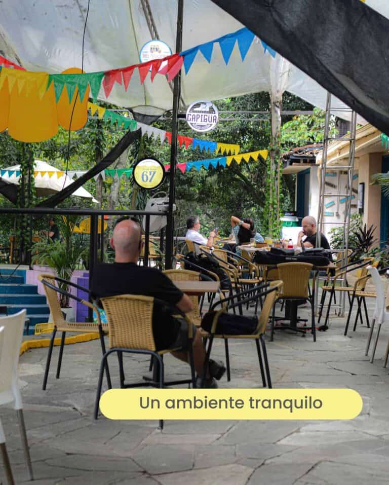 Disfruta de un ambiente tranquilo en un restaurante al aire libre decorado con coloridas banderines y luces, ideal para relajarse y socializar en la naturaleza.