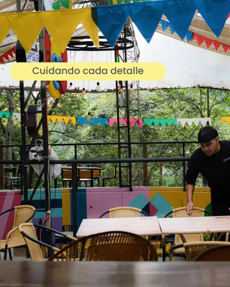 Fiesta al aire libre con decoración colorida, mesas y sillas en un espacio con árboles, ideal para eventos y celebraciones al exterior.