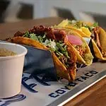 Tacos al estilo mexicano con carne, guacamole, cebolla y cilantro en un plato de restaurante.