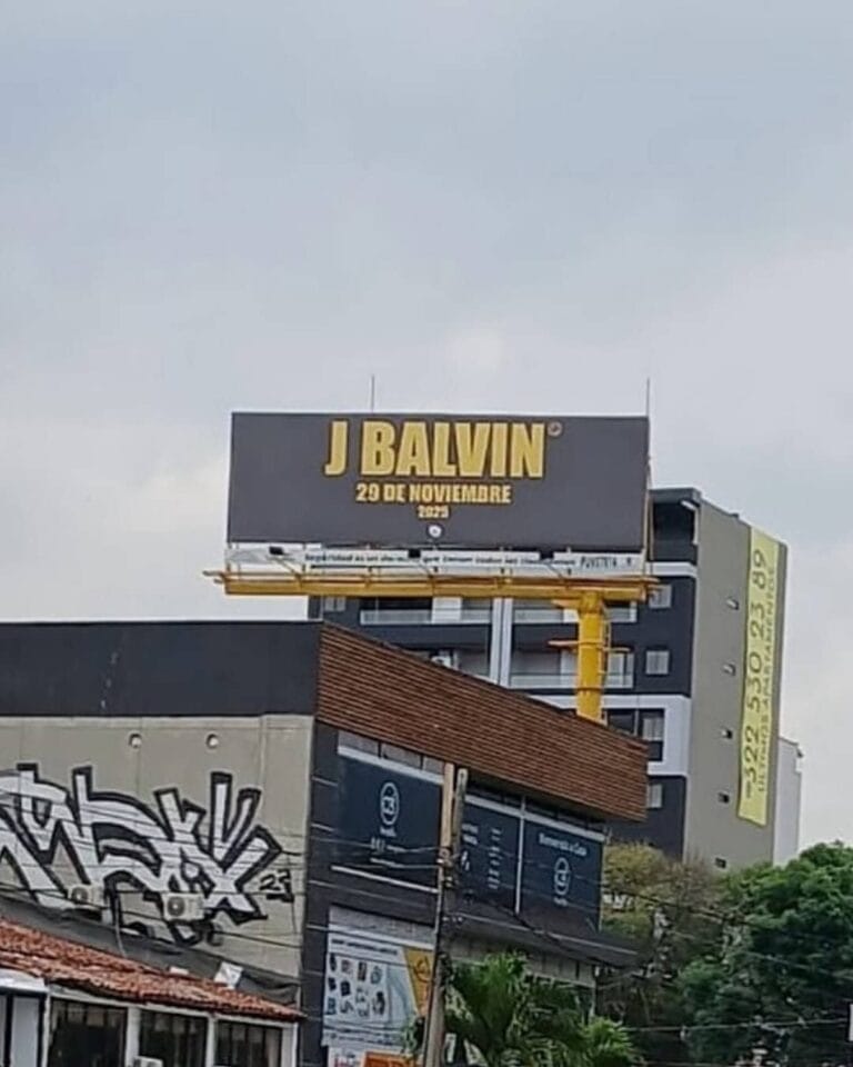 J Balvin cartel en ciudad con anuncios publicitarios y graffitis, promocionando su concierto el 29 de noviembre en Colombia, enfoque en eventos musicales y entretenimiento.
