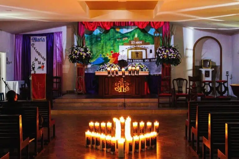 Un décor à thème religieux décoré de bougies et de fleurs dans une église, préparé pour un événement spécial, peut-être une messe ou une cérémonie en l'honneur de la Vierge Marie en Colombie.