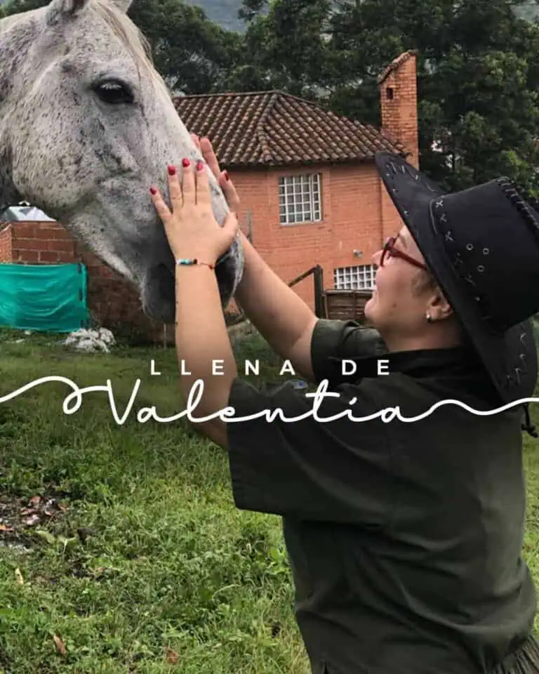 Un cheval blanc touchant la main d'une femme dans un jardin, célébrant l'amour et l'amitié lors d'un événement en plein air en Colombie. Une image émouvante et naturelle pour un événement social avec des animaux, un événement nature.